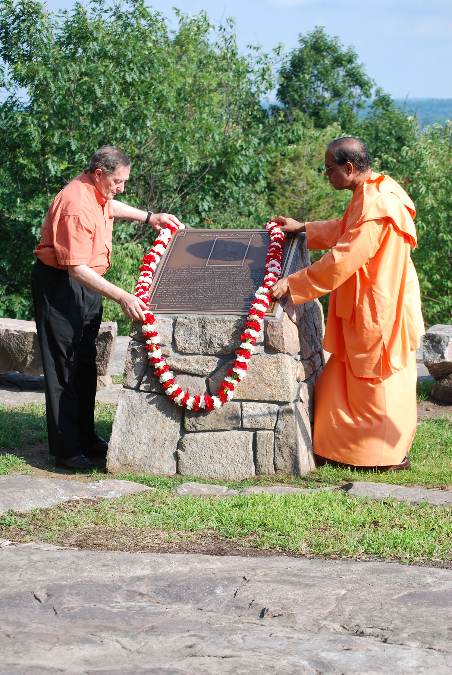 Swami Yuktatamanda and other member laying red and white wreath on Vivekananda rock.