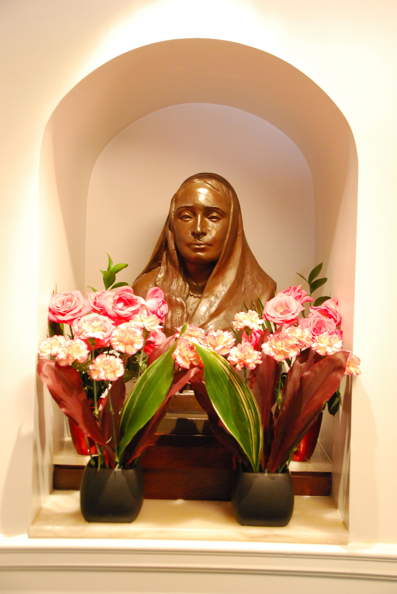 Scupture bust of Sri Sarada Devi surrounded by flowers.