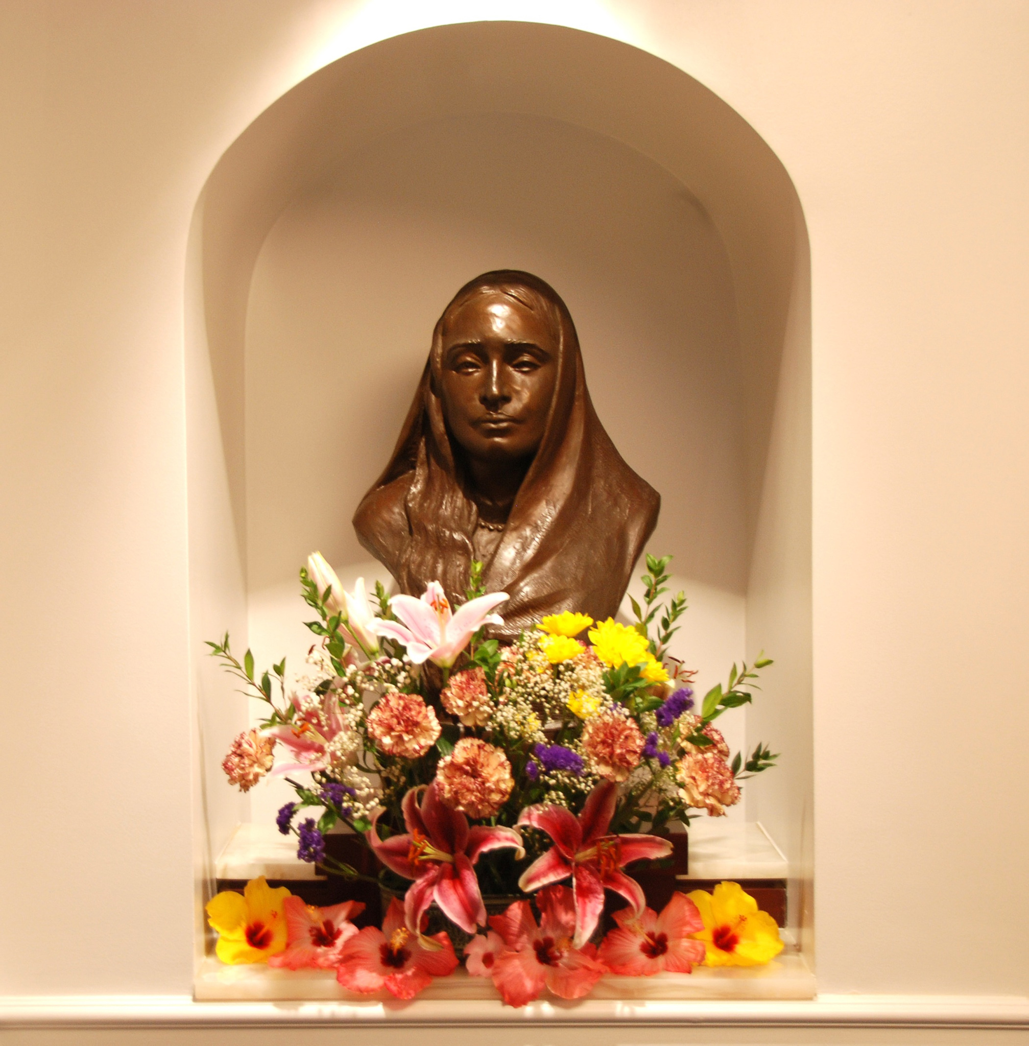 Scupture bust of Sri Sarada Devi surrounded by flowers.
